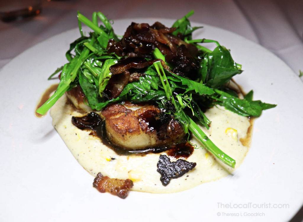 seared scallops served on a bed of sweet corn grits and topped with snow pea greens and bacon