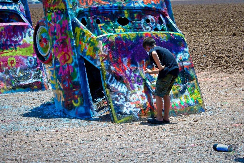 Boy spray painting at Cadillac Ranch