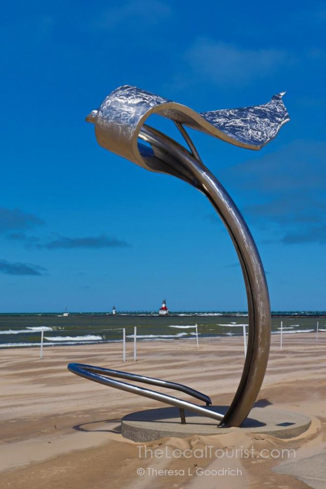 Sculpture with lighthouse in the background at Silver Beach in Saint Joseph, Michigan